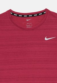 Rød Dri-FIT t-skjorte med rund hals, strukturert stoff og en hvit Nike-logo på brystet. Har en svart og hvit, merket halslinning.