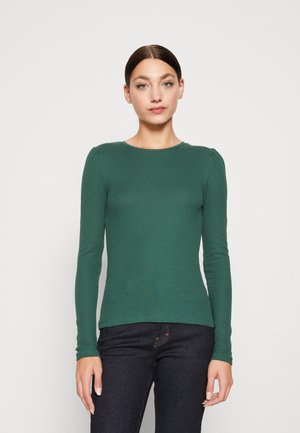 Tricou verde cu mânecă lungă și textură în dungi, cu guler rotund și detalii ușor pliate la umeri, purtat cu blugi închiși la culoare.