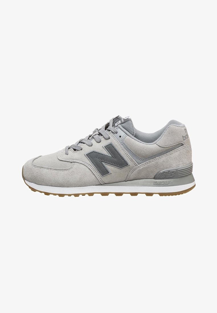 Chaussure de sport en suède gris avec un logo gris foncé, une semelle intermédiaire blanche et une semelle en caoutchouc. Comprend une languette rembourrée et un design à lacets.