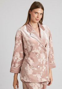 Chaqueta de terciopelo rosa con bordados florales, diseño cruzado, amplios solapas y mangas de tres cuartos. Textura suave y detalles elegantes.
