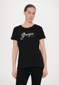 Must musträpitud musta puuvillane T-särk, millel on läikiv, mitmevärviline "Giorgio" logo käsitsi kirjutatud fontidega, ning all on trükitud "Armani Exchange". Lühikesed varrukad ja ümmargune kaelus.