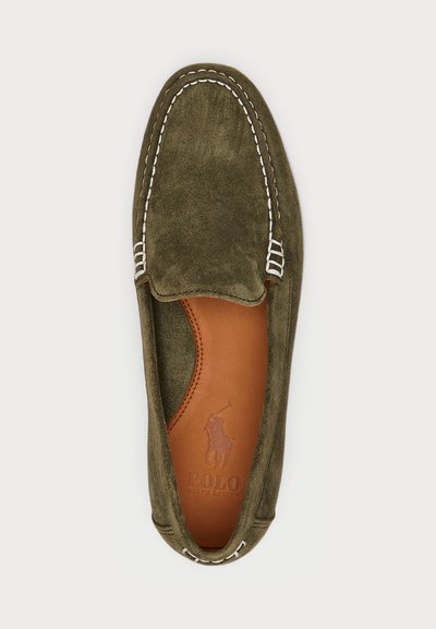 Green suede slip-on shoe with white stitching, rounded toe, and brown leather insole featuring a logo impression. Slip-on design, no laces.