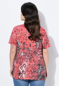 Camiseta de manga corta con un estampado animal vibrante en rojo y negro, que presenta un ajuste relajado y un tejido suave y texturizado.