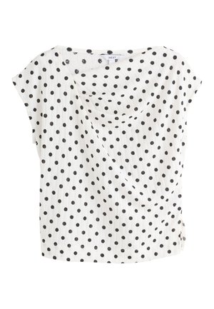 Blouse blanche à manches courtes avec des pois noirs et un col rond modeste, faite en tissu léger et texturé.