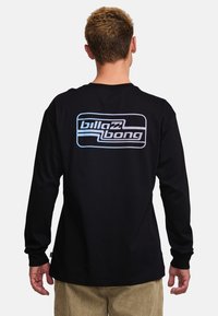 Black long-sleeve shirt with a large blue and white Billabong logo on the back. Made from a soft fabric with a regular fit and smooth texture.