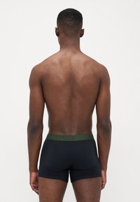 Boxer briefs pretos para homem com um logo verde da Levi's no cós elástico, textura suave e design ajustado, vistos de trás.