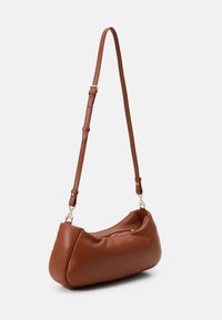 Borsa a spalla in pelle marrone con forma curva, texture morbida, tracolla regolabile e finiture in ottone. Comparto con zip visibile.