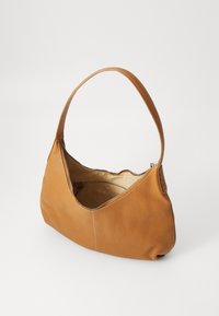 Tan lærveske med en buet design, fremtredende glidelås-lukking, og en enkel skulderstropp. Innvendig har den en lys fòring.