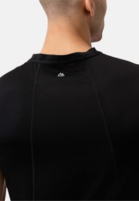 Czarna sportowa koszulka z krótkim rękawem, wykonana z oddychającego materiału, z teksturowanym wzorem oraz małym logo na tylnej części dekoltu.