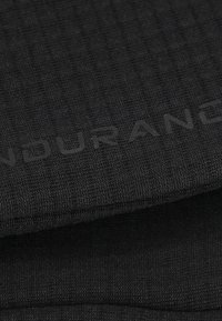 Tissu noir avec un tissage texturé, mettant en avant un logo gris foncé. Le matériau semble durable et fonctionnel, adapté à une utilisation active.