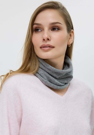 Écharpe en tricot gris avec col montant portée sur un pull rose doux, mettant en valeur sa forme tubulaire et sa texture douillette. Gros plan sur l'encolure.