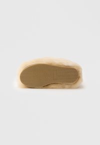 Pantofole in finta pelliccia con esterno beige, texture morbida e suola in gomma con motivo a zigzag per una migliore aderenza e durata.