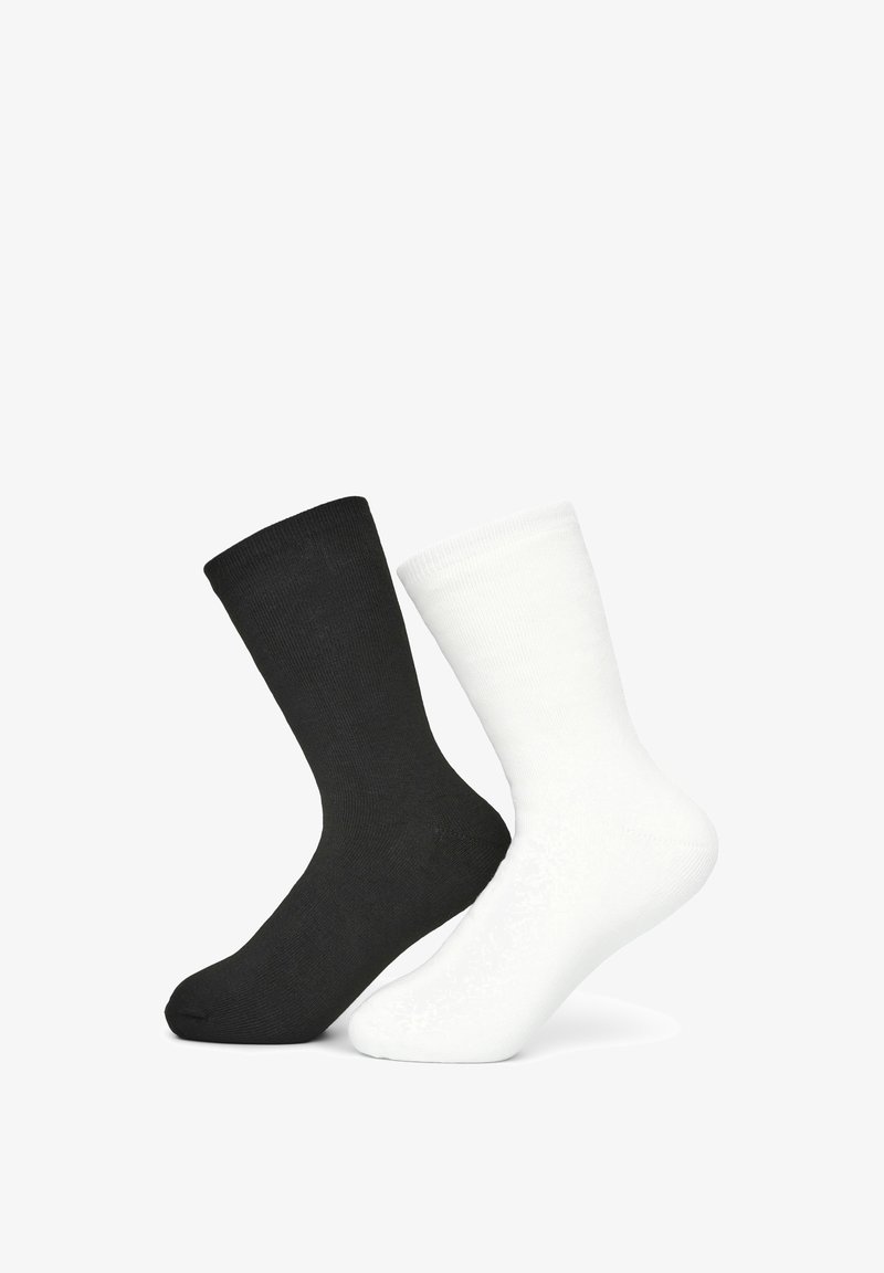 Calzini in cotone bianchi e neri, di lunghezza media, con texture a coste, ciascuno con un design semplice e colori a contrasto, esposti affiancati.