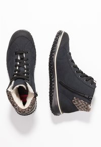 Bottines noires avec tissu texturé, devant à lacets, fermeture éclair sur le côté et semelle en caoutchouc. Doublées en polaire avec des accents motifs sur le col.