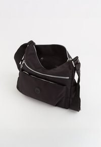 Černá nylonová crossbody taška se stříbrnými zipy, nastavitelným popruhem, přední kapsou a kulatým logem. Měkká textura a praktický design.