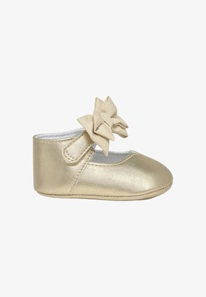 Zapato de bebé metálico dorado con textura suave, punta redondeada y un lazo decorativo de tela en el lateral; cuenta con una correa ajustable.