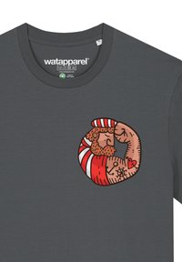 Graues T-Shirt mit einem kreisförmigen Grafikdesign, das einen muskulösen Charakter mit roten und weißen Streifen zeigt, der einen flexenden Arm und Tattoos präsentiert.