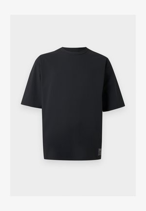 Fekete, túlméretezett rövid ujjú póló környakkal és kis márkajelzés a jobb alsó szegély közelében, egyszerű világos háttér előtt.
