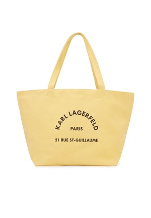 Żółta torba typu tote z podwójnymi uchwytami, z czarnym nadrukiem "KARL LAGERFELD PARIS 21 RUE ST-GUILLAUME" na przodzie.