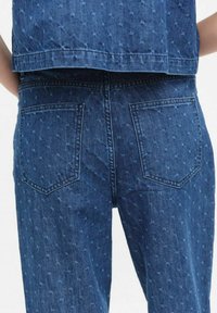 Jeans i denim med en mörkblå nyans som har ett subtilt mönster, två bakfickor och en figurnära silhuett. Tillverkade av bomull.