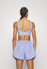 Svetlo modra športna modrc z nizkim hrbtom in usklajenimi hlačkami. Modrc ima subtilen vzorec; hlačke imajo elastičen pas in kontrastne šive.