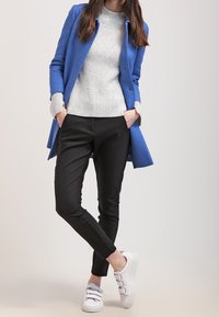 Blue long coat, gray ribbed sweater, black slim pants, and white sneakers with strap details. Smooth fabric and tailored fit.