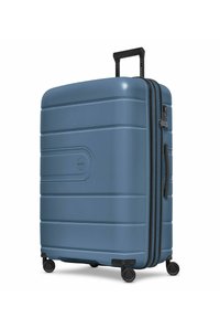 Valise rigide bleue avec quatre roues multidirectionnelles, poignée rétractable, poignée latérale et serrure intégrée sur fond blanc.