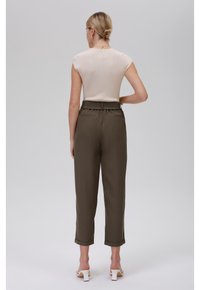 Haut beige à manches courtes style casquette, texture côtelée, associé à un pantalon taille haute vert olive. Le pantalon présente des revers aux chevilles et des poches latérales.