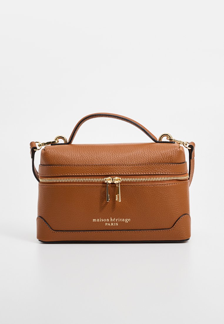 Sac à main en cuir marron au design structuré, doté d'une anse supérieure, d'une fermeture éclair dorée et du nom de la marque en relief à l'avant.