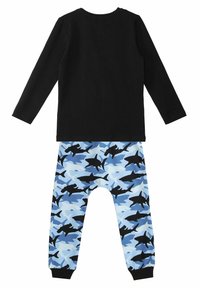 Sort langærmet toppen parret med blå pyjamasbukser med hajprint i sort og varierende nuancer af blå. Elastiske manchetter ved anklerne.