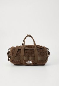 Smeđa teksturirana sportska torba s vanjskom stranom od flisa, dvostrukim ručkama, podesivim naramenicama i bijelim logotipom sprijeda.