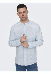 Camicia a righe leggere, blu e bianca, con colletto a fascia e maniche lunghe, realizzata in un tessuto testurizzato. Bottoni sulla parte anteriore.