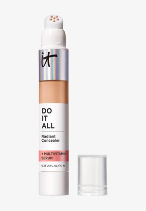 Bâton anti-cernes avec applicateur coussin libérant des gouttes de sérum beige, étiqueté "Do It All Radiant Concealer + Multivitamin Serum", bouchon à côté.