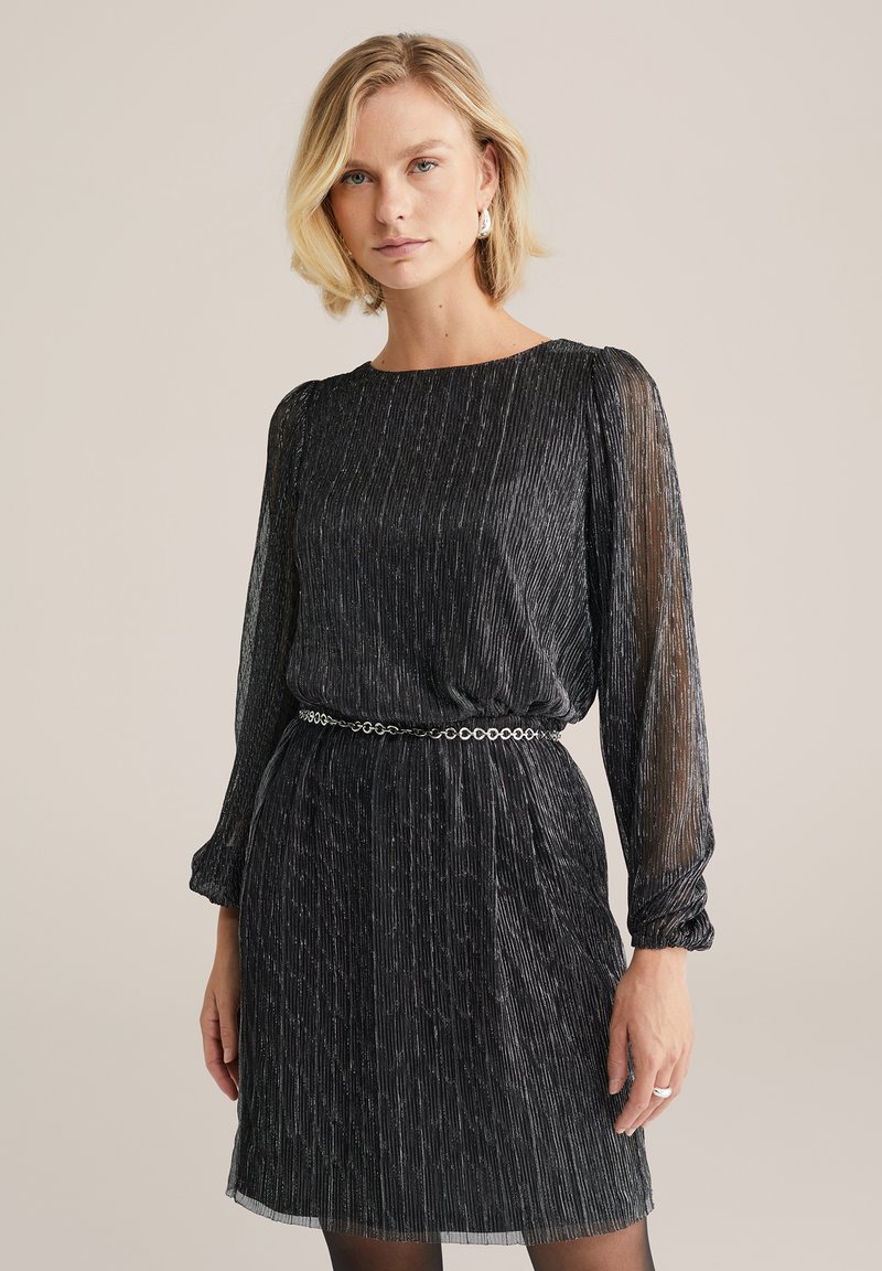 Rochie din chiffon negru cu dungi verticale strălucitoare, mâneci lungi din material transparent, decolteu rotund și talie strânsă accentuată de un brâu din lanț.