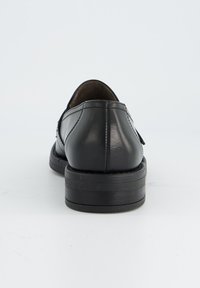 Zwarte leren schoenen met een ronde neus, voorzien van een soepele textuur en een lage, gestapelde hak. Het ontwerp bevat subtiele stiksels.