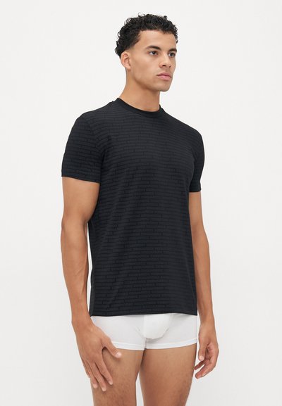 T-shirt noir à manches courtes avec un motif de logo subtil. Fabriqué en tissu léger, avec un col rond et une coupe régulière.