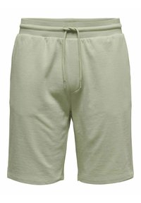 Pantalones cortos de algodón verde claro con cintura elástica, cordón y un ajuste relajado. Presenta una textura suave y bordes dobladillos.