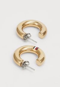 Boucles d'oreilles en métal doré, présentant un design lisse et arrondi, avec une tige en métal argenté et une trio de bandes colorées sur une des boucles.