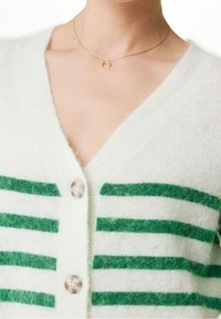 Cárdigan de lana con cuello en V, que presenta rayas verdes sobre una base blanca. Tiene botones transparentes y una textura suave y esponjosa.
