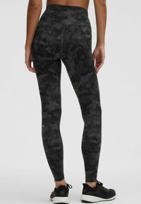 Mustat urheilulegginsit, jotka on valmistettu teksturoidusta kankaasta. Niissä on hillitty kukkamaskuliini kuvio ja korkea vyötärö, joka tuo mukavuutta.