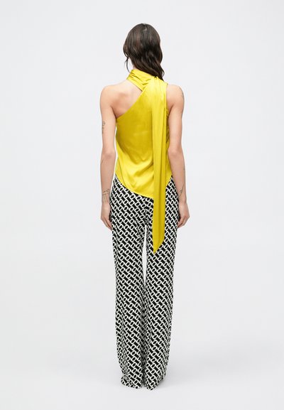 Žiarivý žltý saténový top s jedným ramienkom a záhybovým viazaním v páse, kombinovaný s čierno-bielymi vzorovanými širokými nohavicami. Hladká textúra a plynulý dizajn.