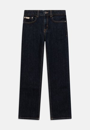 Mørkeblå denimjeans med rett ben-design, kontrasterende oransje sømmer, metallknapp-lukking og en liten merkelapp på baklommen.