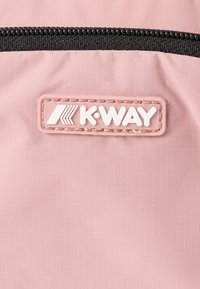 Világos rózsaszín anyag finom textúrával, fekete cipzárral és egy téglalap alakú fehér K-WAY logo folttal.