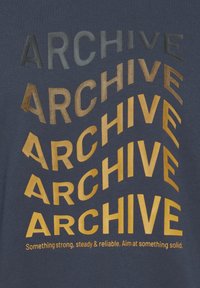 La palabra "ARCHIVO" se repite en un patrón curvado de gris oscuro a amarillo sobre una tela azul, con la frase "Algo fuerte, constante y confiable."