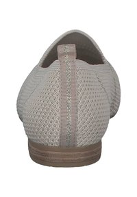 Beige slip-on sko med en tekstureret strikoverdel, der har et metallisk stribe på bagsiden og en lysebrun tekstureret sål.