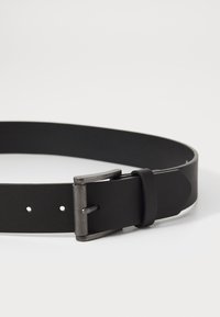 Ceinture en cuir noir avec une boucle en métal au fini brossé. La ceinture possède cinq trous d'ajustement et une texture lisse.