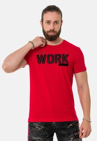 Rotes Baumwoll-T-Shirt mit Rundhalsausschnitt und kurzen Ärmeln, das mit einem auffälligen schwarzen "WORK"-Druck versehen ist. Glatte Textur, lässige Passform.