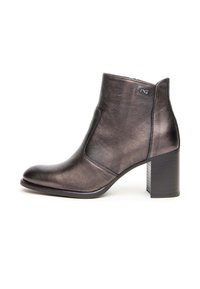 Bottine en cuir métallisé noir avec un talon carré, une pointe effilée et des détails de couture sur les côtés, comportant un petit logo sur le dessus.