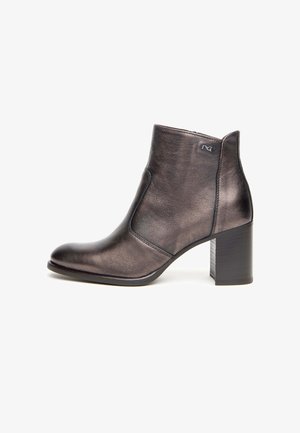 Bottine en cuir métallisé noir avec un talon carré, une pointe effilée et des détails de couture sur les côtés, comportant un petit logo sur le dessus.