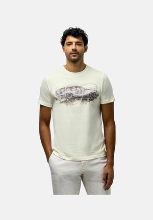 Man wearing off-white t-shirt with a vintage car sketch and "State of Art" text, paired with light-colored pants, standing with hands in pockets.